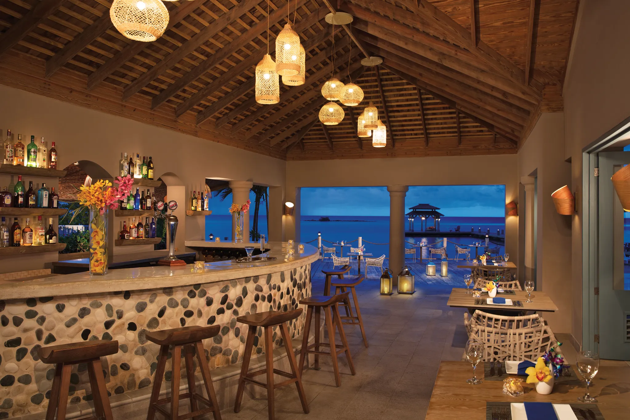 Canoa Bar at Zoëtry Montego Bay Jamaica featuring an open-air oceanfront bar with Caribbean Sea views, rustic wood-beam ceiling, and elegant evening ambiance.