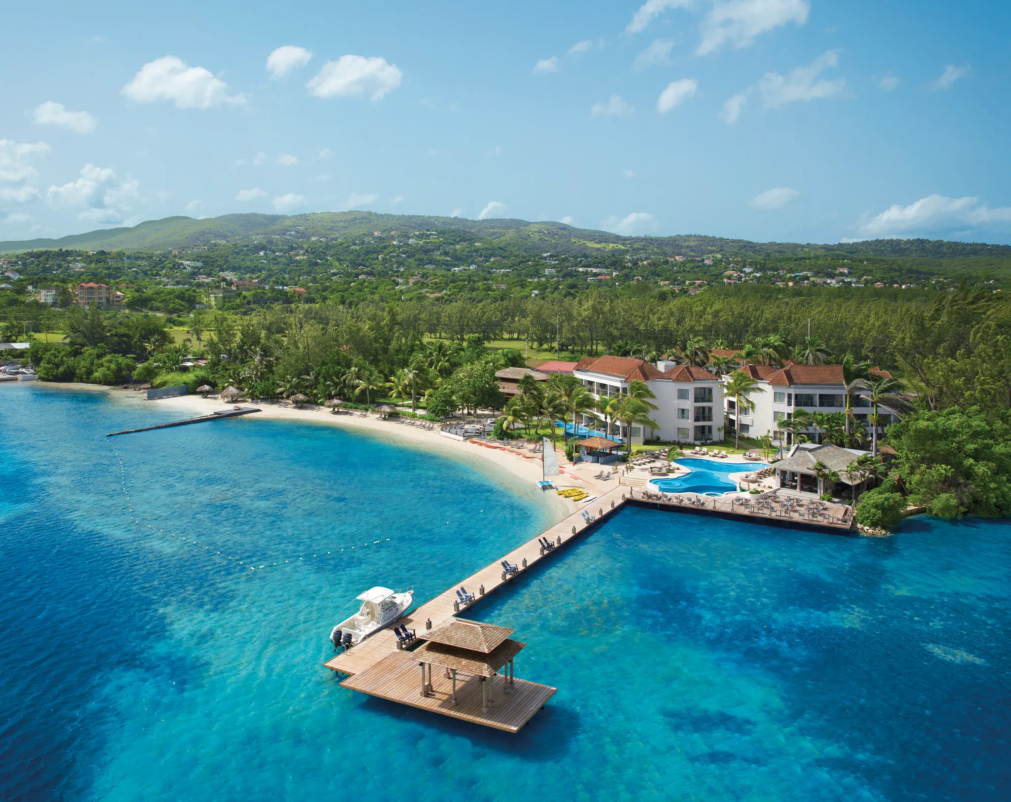 Aerial view of Zoëtry Montego Bay Jamaica featuring a private beach, turquoise Caribbean waters, and a scenic wooden pier.