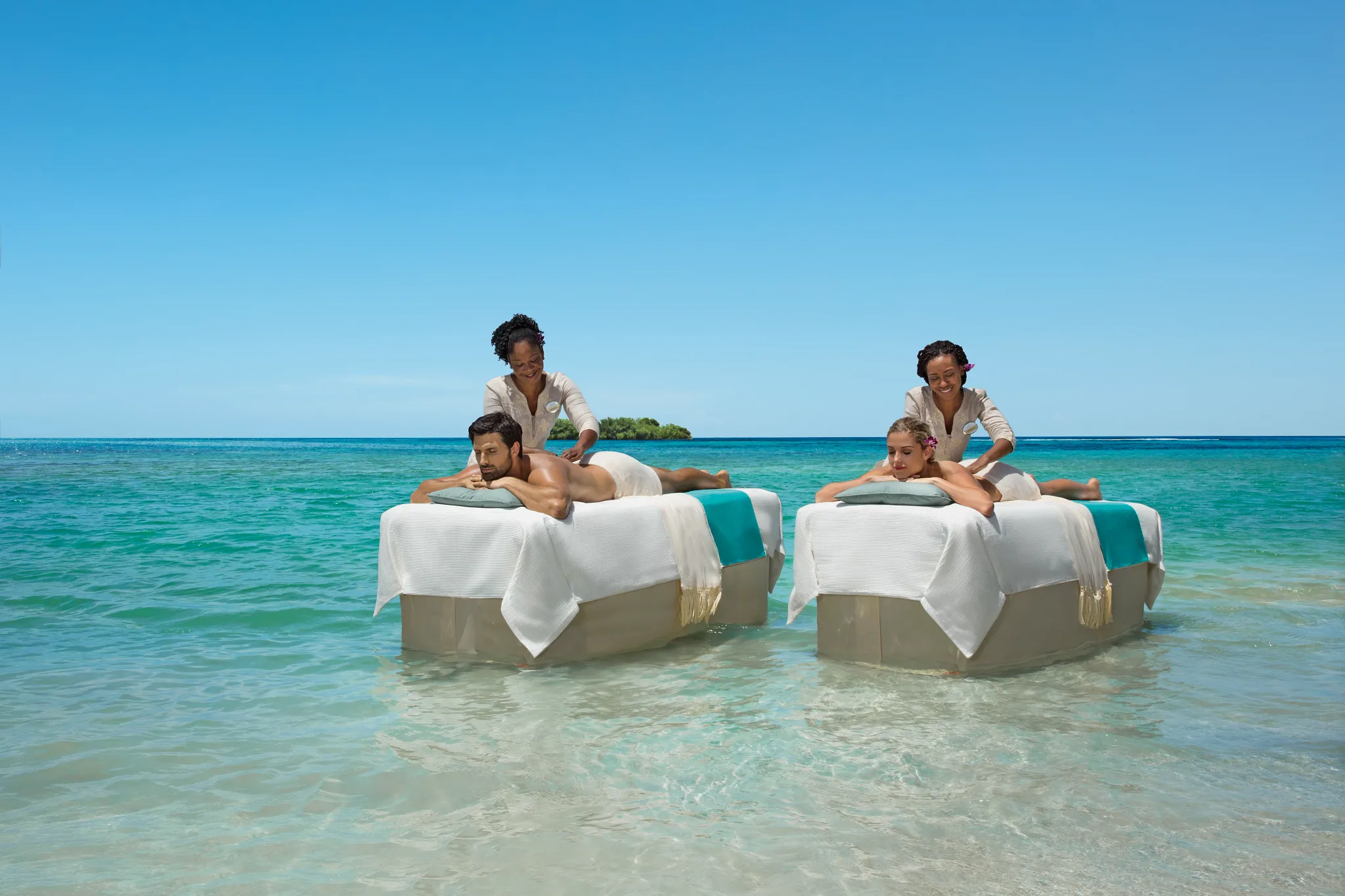 Couples receiving a beachfront massage in shallow Caribbean waters at Zoëtry Montego Bay Jamaica.