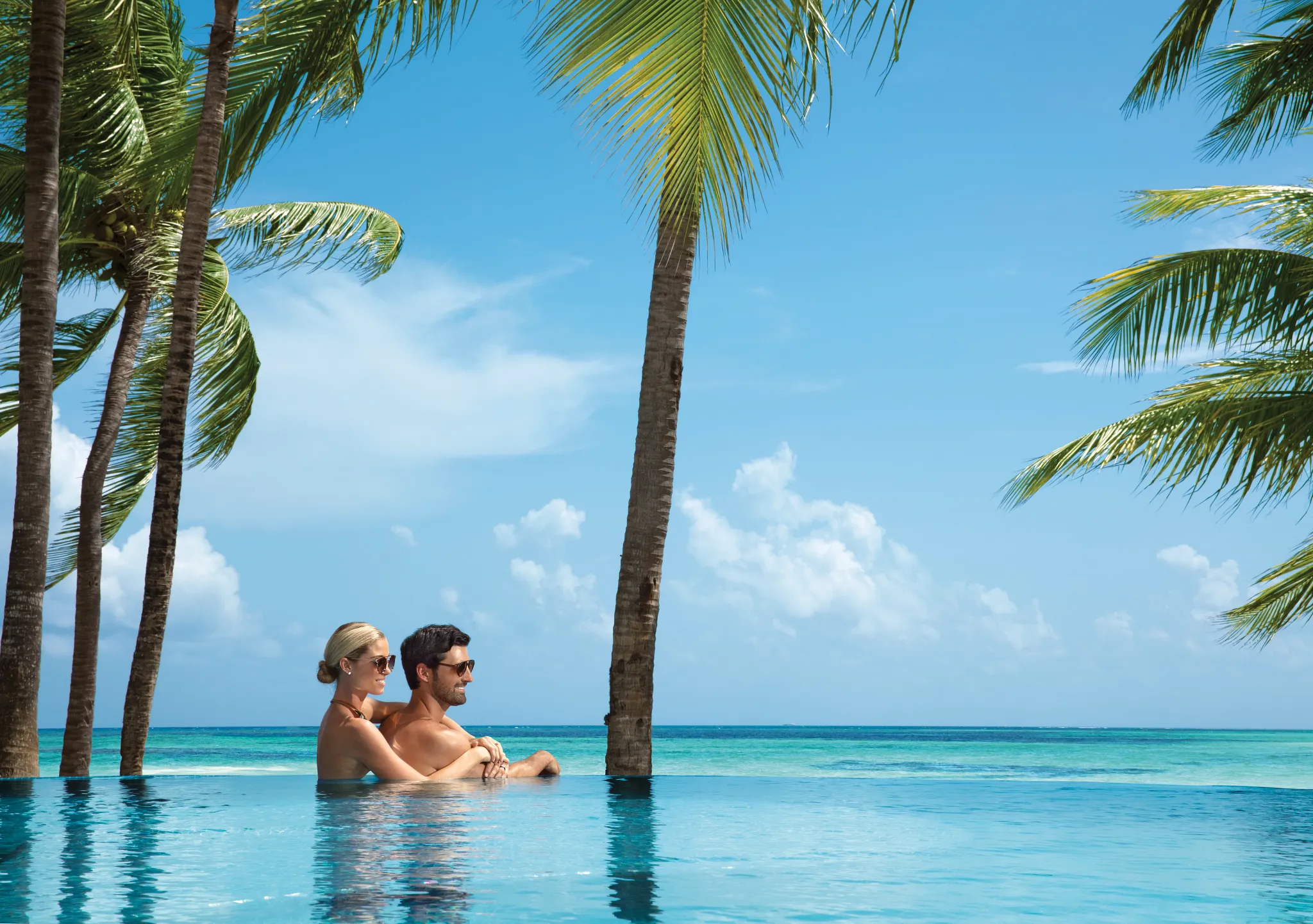 Couple relaxing together in an infinity pool overlooking the Caribbean Sea at Zoëtry Montego Bay Jamaica.