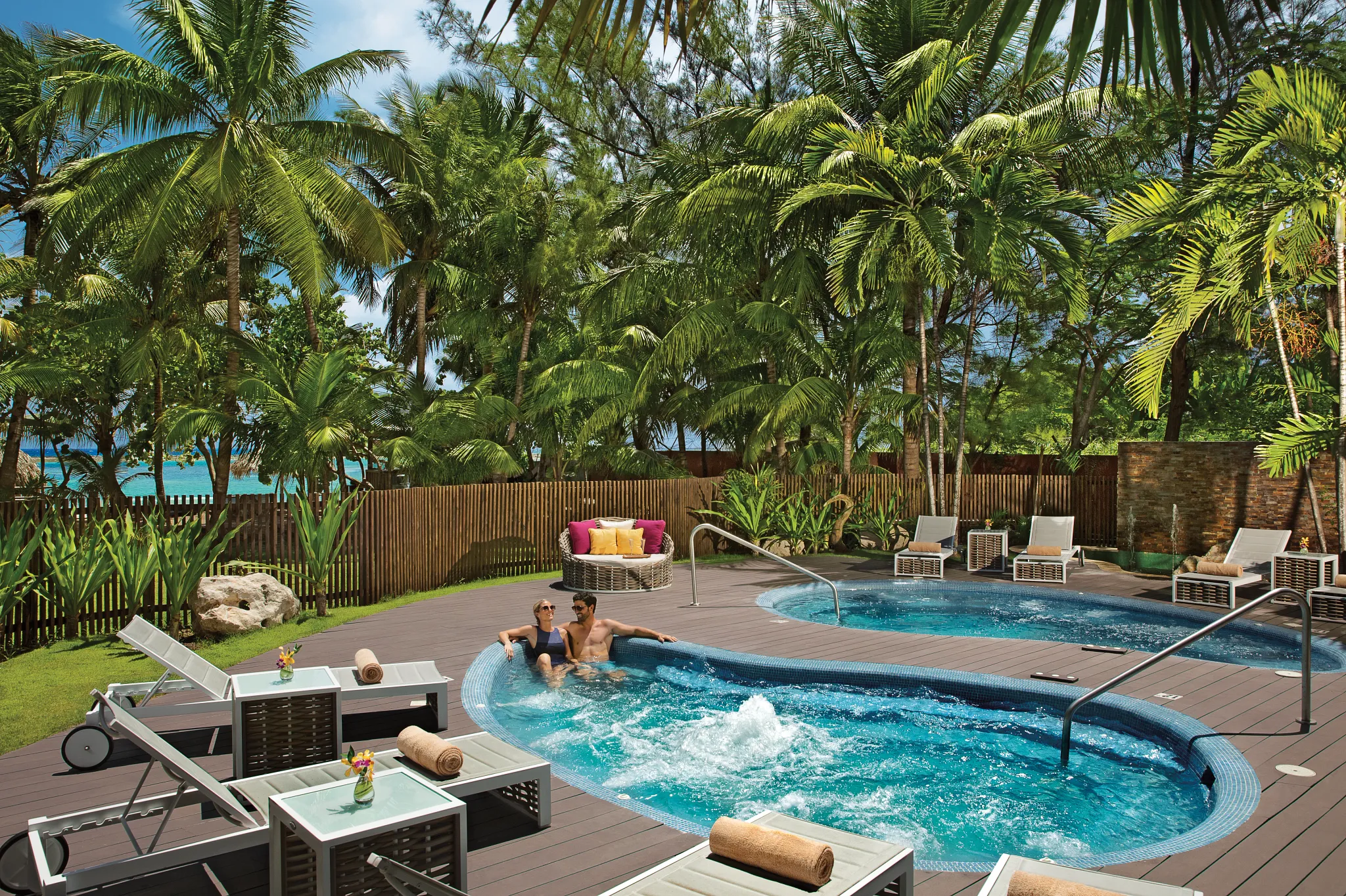 Couple relaxing in an outdoor whirlpool surrounded by palm trees at Zoëtry Montego Bay Jamaica.