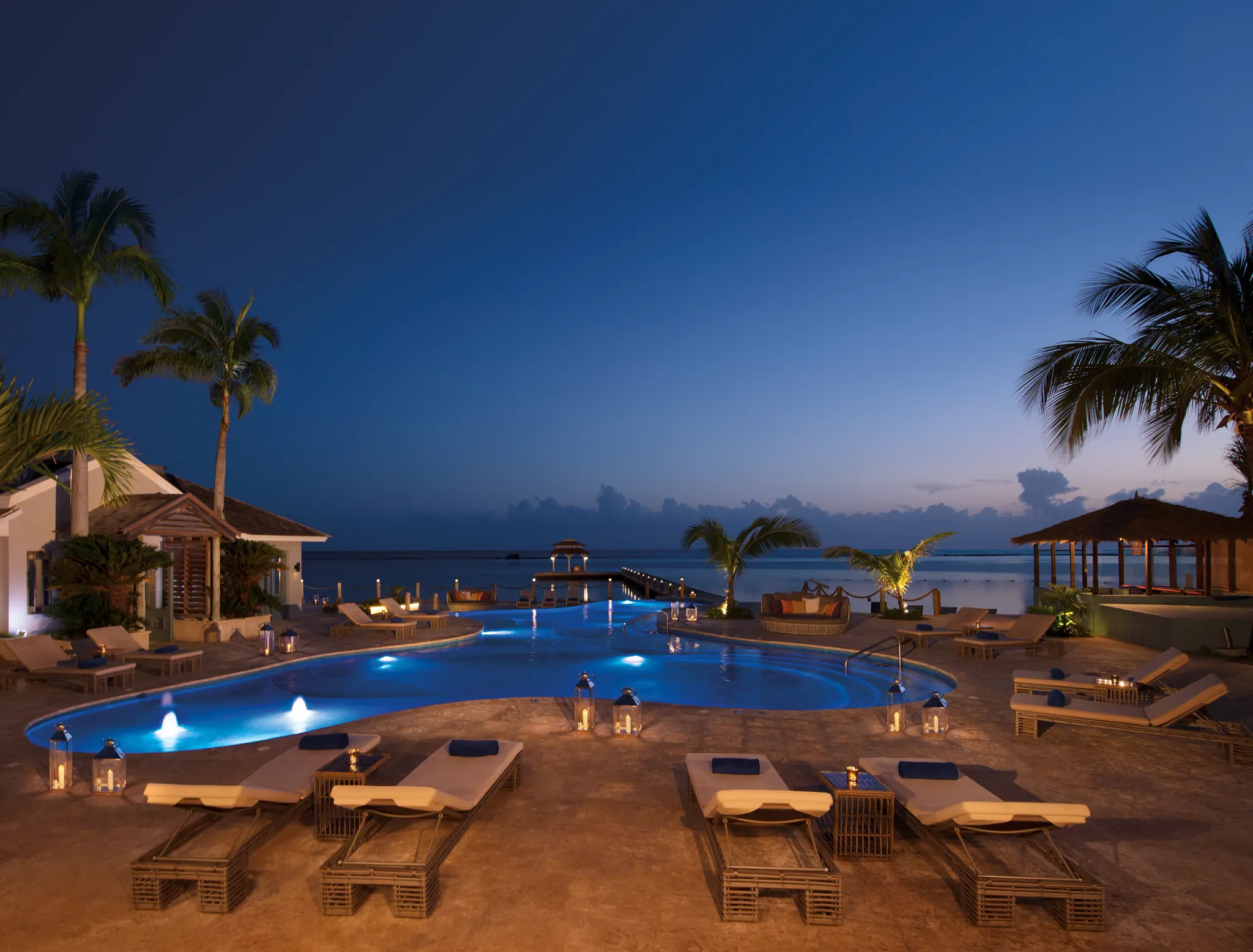 Evening view of the illuminated pool and pier at Zoëtry Montego Bay Jamaica under a twilight sky.