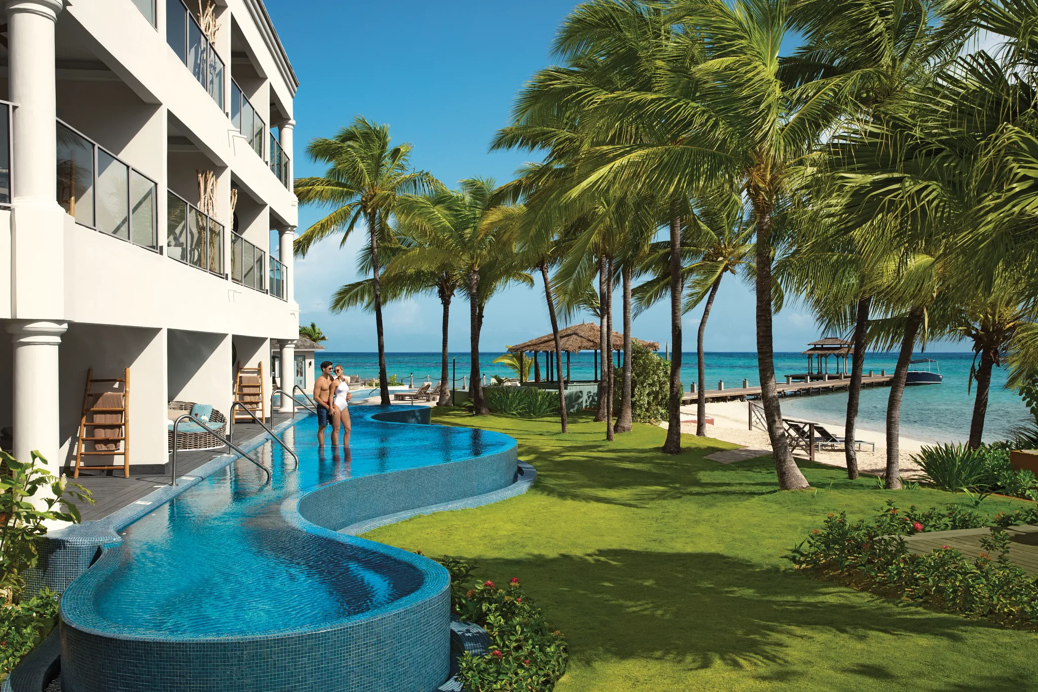 Couple enjoying a swim-out suite pool at Zoëtry Montego Bay Jamaica with ocean views and palm trees.